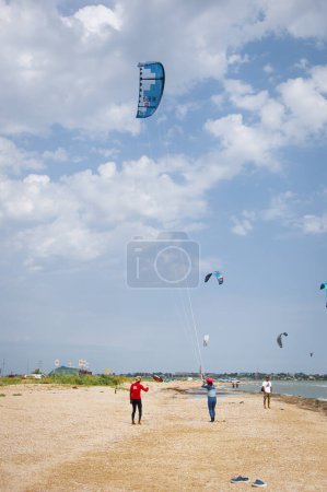 Photo for Henichesk, Ukraine - July 12, 2021: Kitesurfing. Practicing kitesurfing at summer beach. Active travel sport recreation. Kitesurfer doing tricks. Enjoy riding kite surf board. Kitesurfing camp spot. - Royalty Free Image