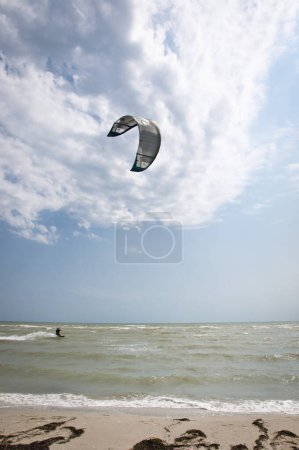 Photo for Henichesk, Ukraine - July 12, 2021: Active sport. Kiteboarder riding kiteboard with power kite. Watersport adrenaline. Kitesurfing. Active athlete on kiteboard hold control bar practicing kitesurfing. - Royalty Free Image