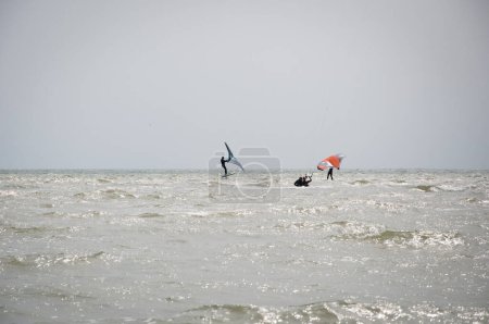 Photo for Henichesk, Ukraine - July 12, 2021: Kitesurfing. Extreme sport and watersport in summer. Paragliding and wakeboarding. Man rides a kite. Kitesurfing on waves of sea. Freestyle surf. Sailing sport. - Royalty Free Image