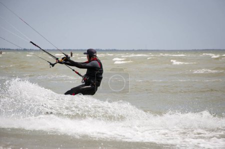 Photo for Henichesk, Ukraine - July 12, 2021: Kitesurfing. Extreme sport and watersport in summer. Paragliding and wakeboarding. Man rides a kite. Kitesurfing on waves of sea. Freestyle surf. Sailing sport. - Royalty Free Image