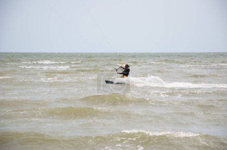 Téléchargez les photos : Henichesk, Ukraine - juillet 12, 2021 : Surfeur en combinaison faire astuce. Athlète kitesurf sur planche de cerf-volant. Kitesurf kitesurf kitesurf kitesurf dans l'océan. Kitesurf. Paysage marin avec surfeur en vagues. - en image libre de droit