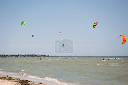 Téléchargez les photos : Henichesk, Ukraine - 12 juillet 2021 : Kitesurf. Pratiquer le kitesurf à la plage d'été. Kitesurfer fait des tours. Les gens aiment faire du kite surf board. Camp de kitesurf. Kitesurfer kitesurf. - en image libre de droit