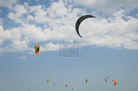 Photo for Henichesk, Ukraine - July 12, 2021: Kitesurfing. Practicing kitesurfing at summer beach. Kitesurfer doing tricks. People enjoy riding kite surf board. Kitesurfing camp spot. Kitesurfer kitesurfing. - Royalty Free Image