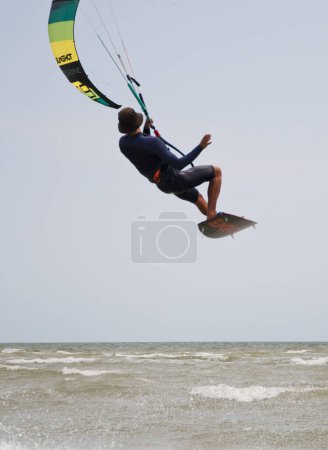 Photo for Henichesk, Ukraine - July 12, 2021: Ocean with kiteboarder riding kiteboard. Watersport adrenaline adventure activity. Kitesurfing. Active athlete on kiteboard hold control bar practicing kitesurfing. - Royalty Free Image