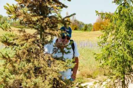 Senior old Hispanic man in summer style with Cuban cap outdoor hiding in spring nature park.