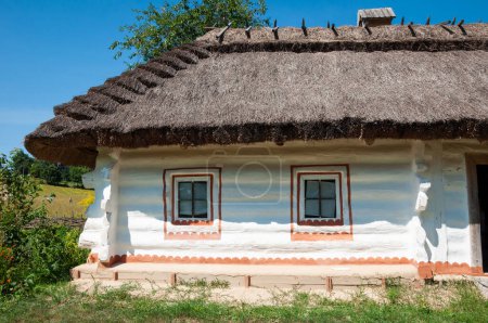Authentic old village cottage with thatched roof folk architecture in ethnographic museum in Pyrohiv, Ukraine. Madeira travel and landmarks. Traditional colorful house with thatched roof.