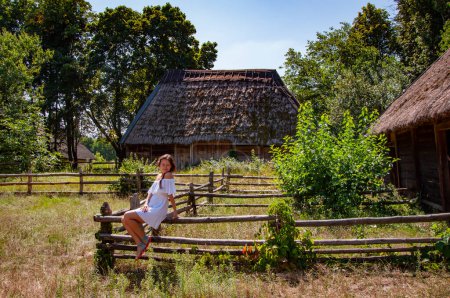 Ukraine folk authentic house. Thatched house in Ukrainian village. Woman in summer farm. Authentic Ukrainian architecture. Woman outdoor. Ukrainian woman in summer village cottage. Grazing cattle.