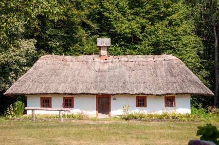 Authentic Ukrainian house in countryside. Summer village in Ukraine. Old folk thatched house. Ukrainian traditional rustic house. Rural countryside in summer ranch. Architecture. Crumbling clay walls.