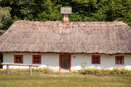 Authentic Ukrainian house in countryside. Summer village in Ukraine. Old thatched house. Ukrainian traditional rustic house. Rural countryside in summer ranch. Architecture. Weathered thatched roof.