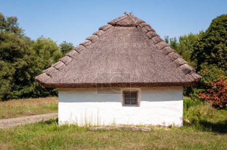 Authentic Ukrainian house in countryside. Summer village in Ukraine. Old folk thatched house. Ukrainian traditional rustic house. Rural countryside in summer ranch. Architecture culture.