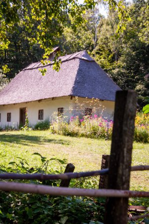 Authentic Ukrainian house in countryside. Summer village in Ukraine. Old folk thatched house. Ukrainian ethnographic traditional rustic house. Rural countryside in summer ranch. Architecture.