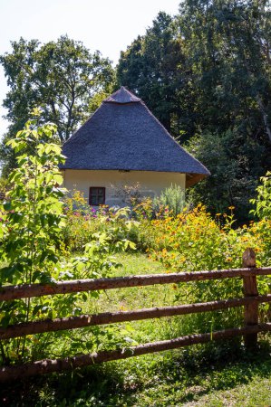 Authentic Ukrainian house in countryside. Summer village in Ukraine. Old folk thatched house. Ukrainian traditional rustic house. Rural countryside in summer ranch. Architecture exterior.