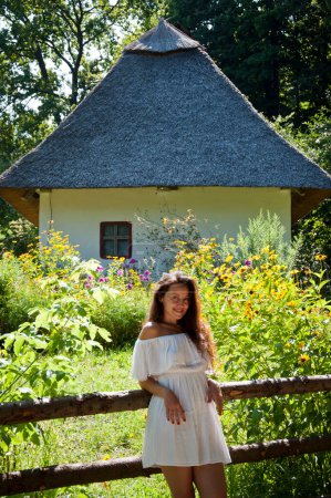 Ukraine folk authentic house. Thatched house in Ukrainian village. Woman in summer farm. Authentic Ukrainian architecture. Woman outdoor. Ukrainian woman in summer village cottage building.