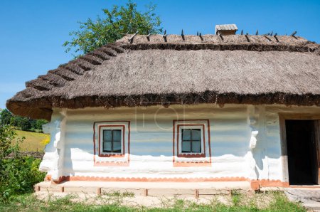 Authentic old village cottage with thatched roof folk architecture in ethnographic open-air museum in Pyrohiv, Ukraine. Old authentic wooden house with a thatched roof.