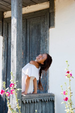 Photo for Young romantic woman in white dress at village cottage house in summer countryside outdoor. Beautiful woman. - Royalty Free Image