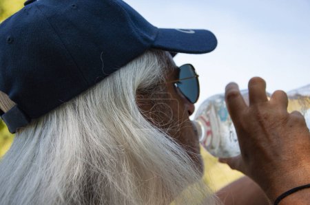 Durstige Senioren verspüren Durst und trinken Wasser aus der Sportflasche für einen gesunden Wasserhaushalt. Heißer Sommer.