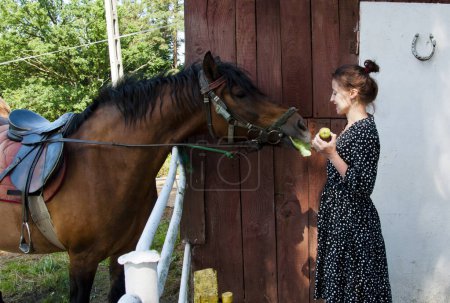 Woman with horse in stable at countryside ranch. Girl horse rider in summer outdoor. Equestrian and horseback riding. Horse stallion equine with Hispanic woman girl. Countryside ranch. Vintage style.