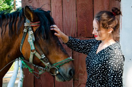 Woman with horse in stable at countryside ranch. Girl horse rider in summer outdoor. Equestrian and horseback riding. Horse stallion equine with woman girl. Countryside ranch. Expansive ranchland.