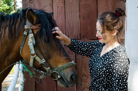 Woman with horse in stable at countryside ranch. Girl horse rider in summer outdoor. Equestrian and horseback riding. Horse stallion equine with Hispanic girl. Countryside ranch. Rancher lifestyle.