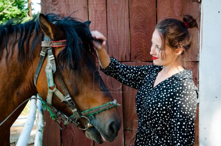 Woman with horse in stable at countryside ranch. Girl horse rider in summer outdoor. Equestrian and horseback riding. Horse stallion equine with woman girl. Countryside ranch. Ranching heritage.