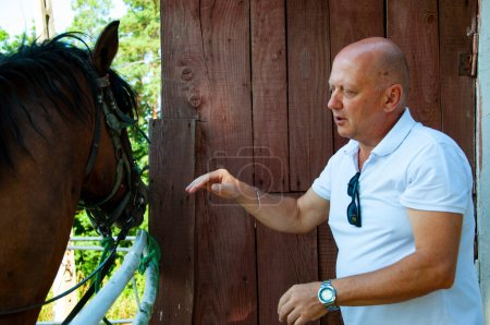 Mann mit Pferd im Stall auf der Ranch. Mann reitet im Sommer im Freien. Reiten und Reiten. Pferdehengst Pferd mit kaukasischen Mann. Ranch auf dem Land. Pferdestall.