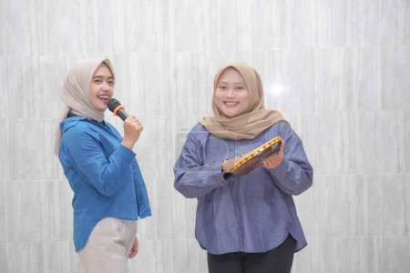 Zwei asiatische Indonesierinnen tragen Hijabs in hellblauer und dunkelblauer Kleidung