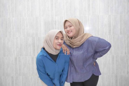 Zwei asiatische Indonesierinnen tragen Hijabs in hellblauer und dunkelblauer Kleidung