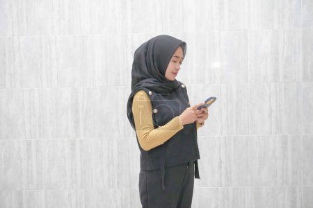 Expression of an Asian Indonesian woman wearing a black hijab with yellow sleeves