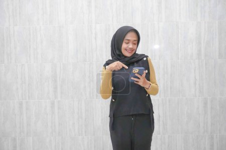Ausdruck einer asiatischen Indonesierin, die einen schwarzen Hijab mit gelben Ärmeln trägt