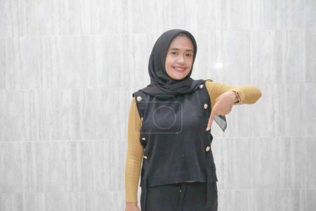 Ausdruck einer asiatischen Indonesierin, die einen schwarzen Hijab mit gelben Ärmeln trägt