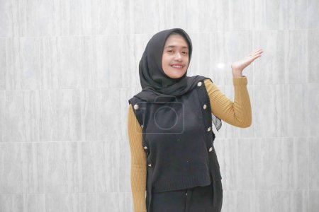 Expresión de una mujer indonesia asiática con un hiyab negro con mangas amarillas