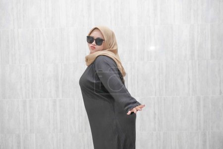 Expresión de una mujer indonesia asiática vestida con un hiyab marrón y ropa negra
