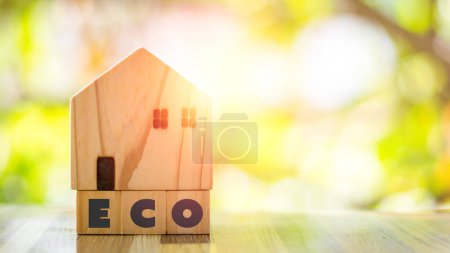 Umweltfreundliches Haus-Konzept. Holzhaus auf dem Block mit Öko-Alphabet auf grünem Hintergrund. 