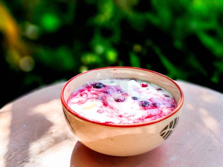 Kéfir casero, suero de leche o yogur con bayas mezcladas con probióticos en un tazón sobre una mesa de madera en un café. Comida y bebida de moda y saludable