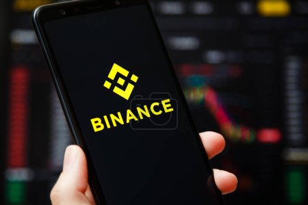 Foto de Ukraine, Odessa - June, 1 2021: Binance mobile app running at smartphone screen with a trading page at background. Binance one of the world's leading cryptocurrency exchange and trading platform. - Imagen libre de derechos