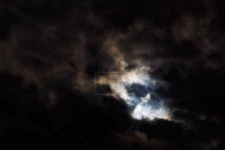 Un eclipse solar parcial del 25 de octubre de 2022 capturado a través de nubes oscuras malhumoradas, la fase máxima visible desde Europa, Rumania.