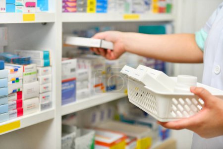 Foto de Farmacéutica mujer química de pie recarga los estantes con nuevas existencias en farmacia - Imagen libre de derechos