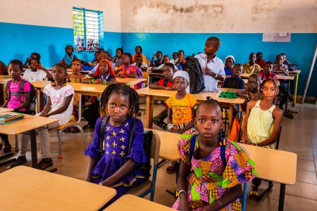 Photo for MBOUR, SENEGAL - DECEMBER Circa, 2020. Unidentified serious and sad african children sitting at desks in a classroom in a primary school. New class with new desks, roof, paintings. Due to international NGO help. - Royalty Free Image