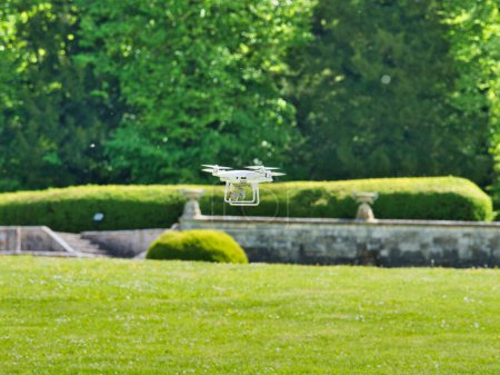 Photo for White quadrocopter flying under grass, close-up. New unmanned aerial copter. Electronics innovation.Aeromodelling. Modern Technologies. - Royalty Free Image