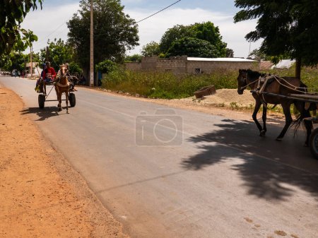 Foto de MBOUR, SENEGAL - ENERO CIRCA, 2022. Transporte local de personas y entregas con burro o carro de caballos en las ciudades. Personas africanas sentadas en el transporte tradicional local. - Imagen libre de derechos