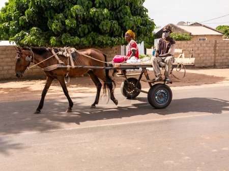 Foto de MBOUR, SENEGAL - ENERO CIRCA, 2022. Transporte local de personas y entregas con burro o carro de caballos en las ciudades. Personas africanas sentadas en el transporte tradicional local. - Imagen libre de derechos