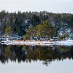 Winter landscape with forest and snow covered rocks, Beauiful reflection in the lake waters. Norway.