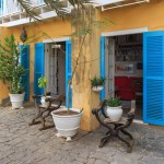 Boa Vista, Cape Verde- March 22, 2018: A cozy cafe garden in Sal Rei, with rustic wooden furniture and vibrant blue shutters. 