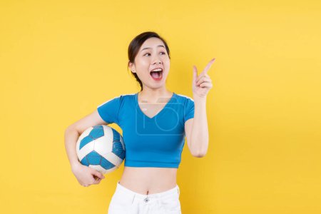Téléchargez les photos : Portrait de jeune fille dynamique tenant le ballon à la main isolé sur fond jaune - en image libre de droit