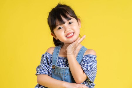 Foto de Retrato de una hermosa chica asiática, aislada sobre fondo amarillo - Imagen libre de derechos