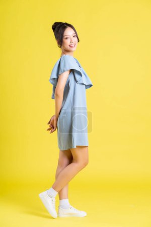 Foto de Retrato de mujer asiática en falda posando sobre fondo amarillo - Imagen libre de derechos