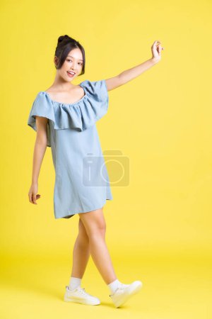 Foto de Retrato de mujer asiática en falda posando sobre fondo amarillo - Imagen libre de derechos