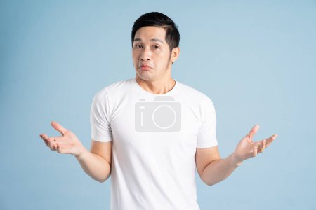 Téléchargez les photos : Portrait masculin asiatique posant sur fond bleu - en image libre de droit