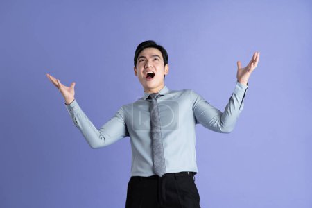 Retrato de hombre de negocios asiático posando sobre fondo púrpura