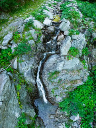 Téléchargez les photos : Un ruisseau de montagne tombant de gros rochers à travers un canyon rocheux et formant une cascade. Là, il crée un petit étang entouré de grandes pierres. Massif Parang, Carpates, Roumanie - en image libre de droit